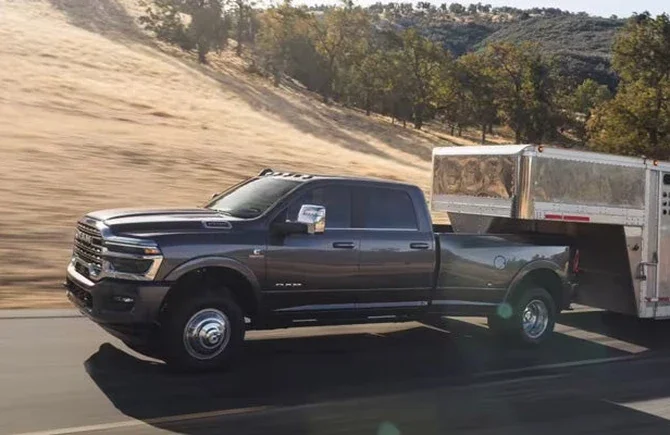 Gray 2026 Ram 3500 dually towing a livestock trailer along a country road