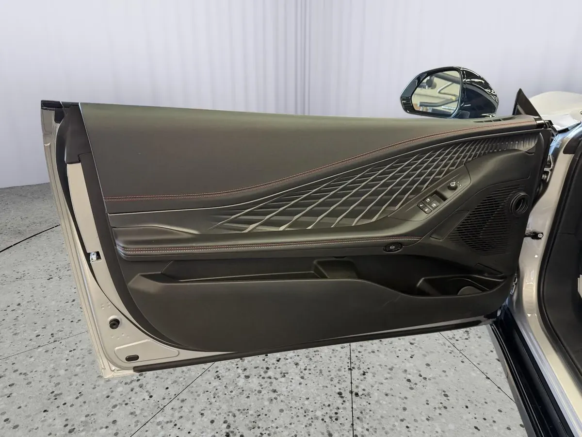 The driver's door open, showing the door panel and speaker grille.
