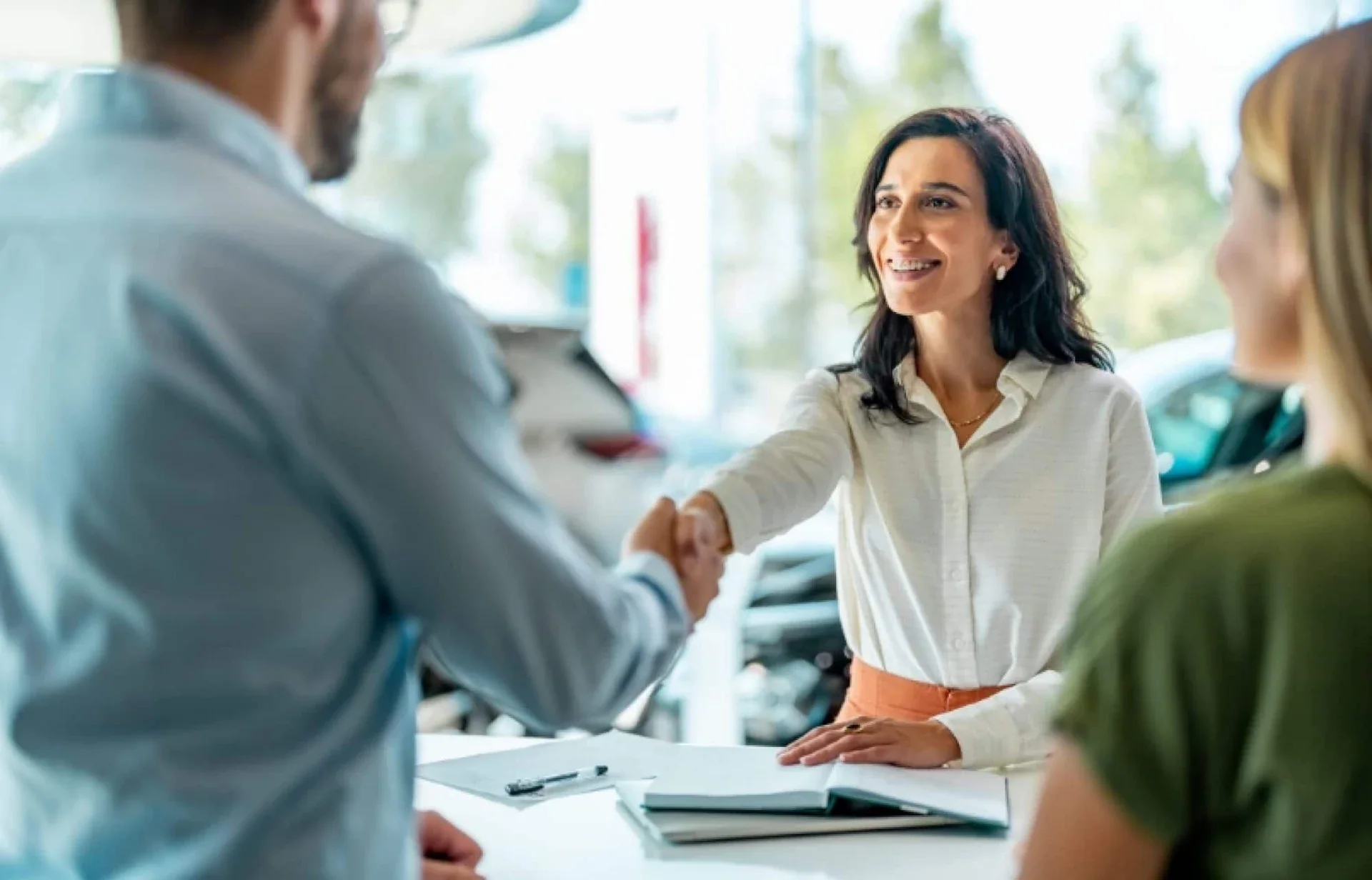 A customer shaking hands across the desk after finishing paperwork.