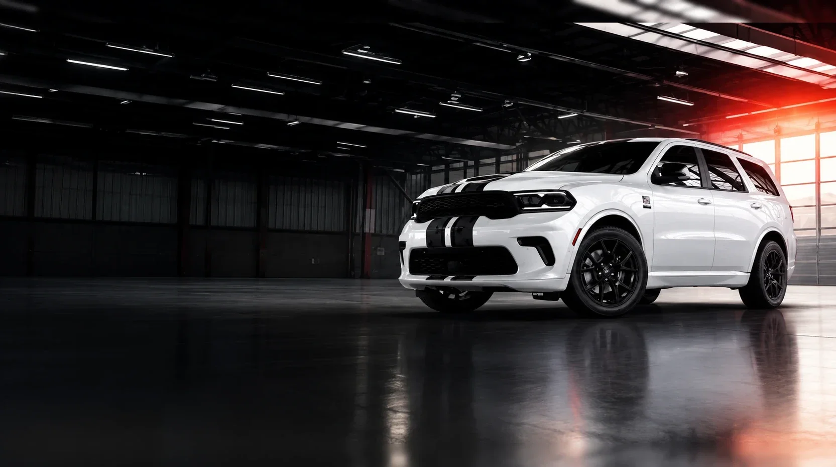 A white Dodge Durango with black hood stripes standing inside a dark warehouse, lit from a doorway on the right.