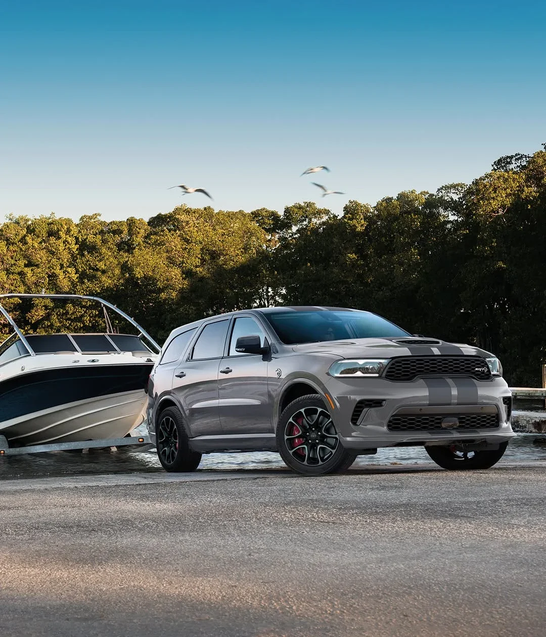 A grey Dodge Durango SRT parked beside a boat on a trailer.
