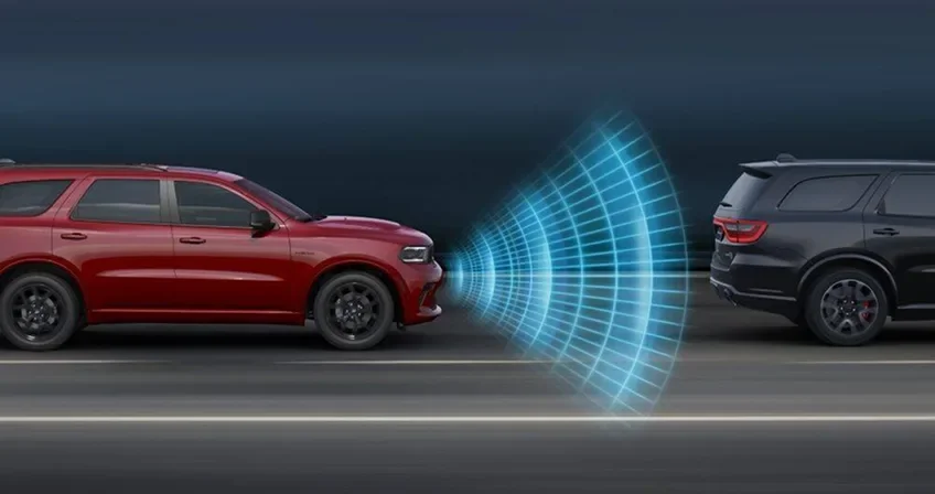 Red Dodge Durango following a dark vehicle with blue sensor waves between them