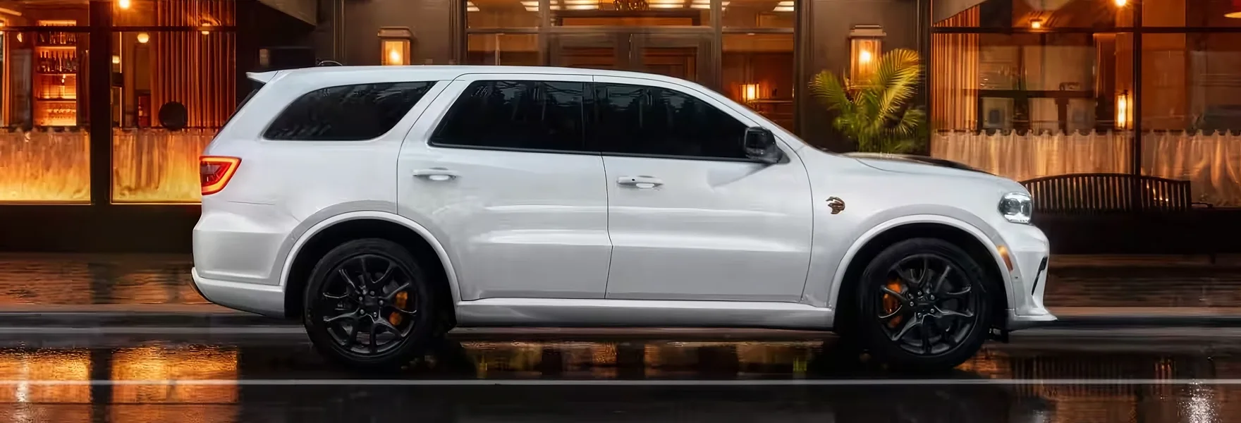 White Dodge Durango parked in profile in front of a lit building at night