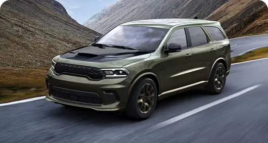 Olive Dodge Durango cornering on a green mountain road