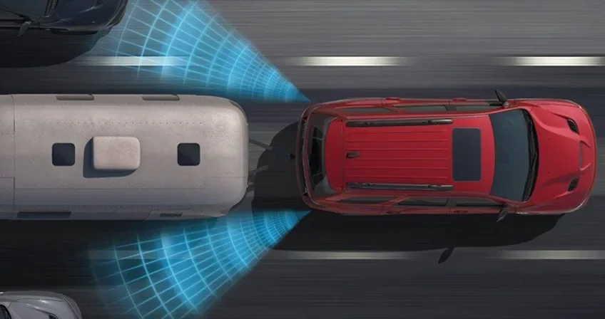 Overhead illustration of a red Durango towing a trailer with blind-spot sensor waves