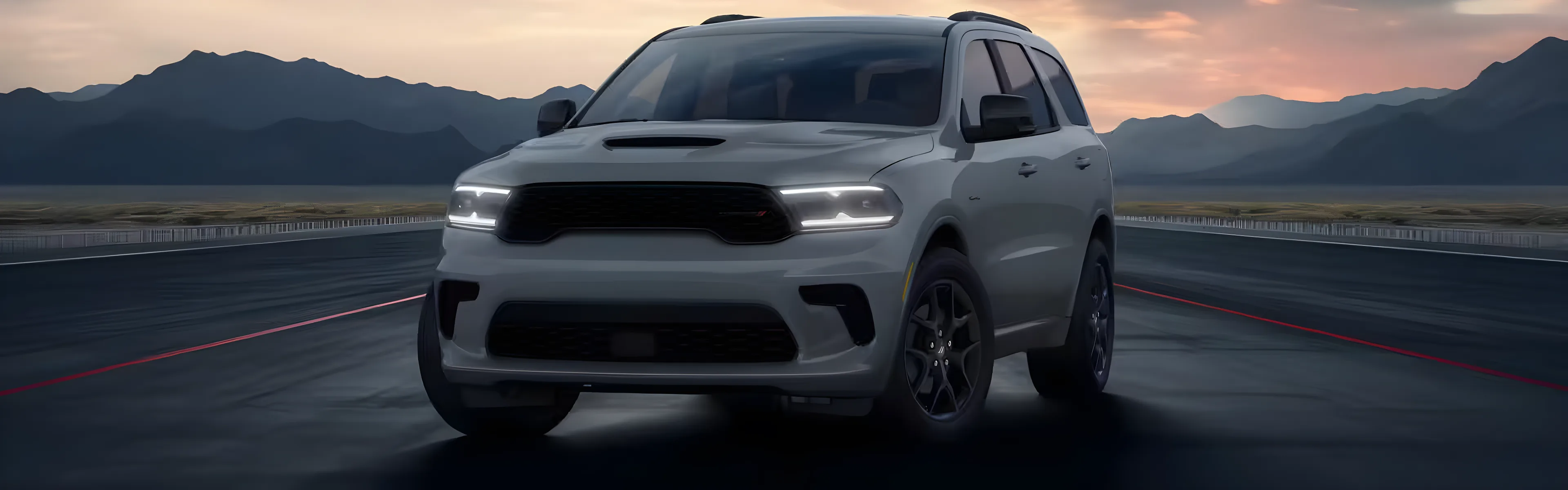 Grey Dodge Durango head-on at dusk with mountains behind