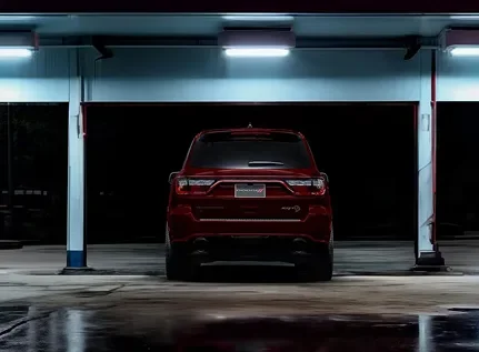 Red Dodge Durango parked in a dark concrete garage, rear view