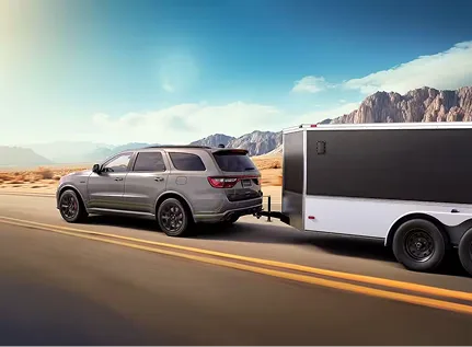Grey Dodge Durango towing a white trailer through desert scenery