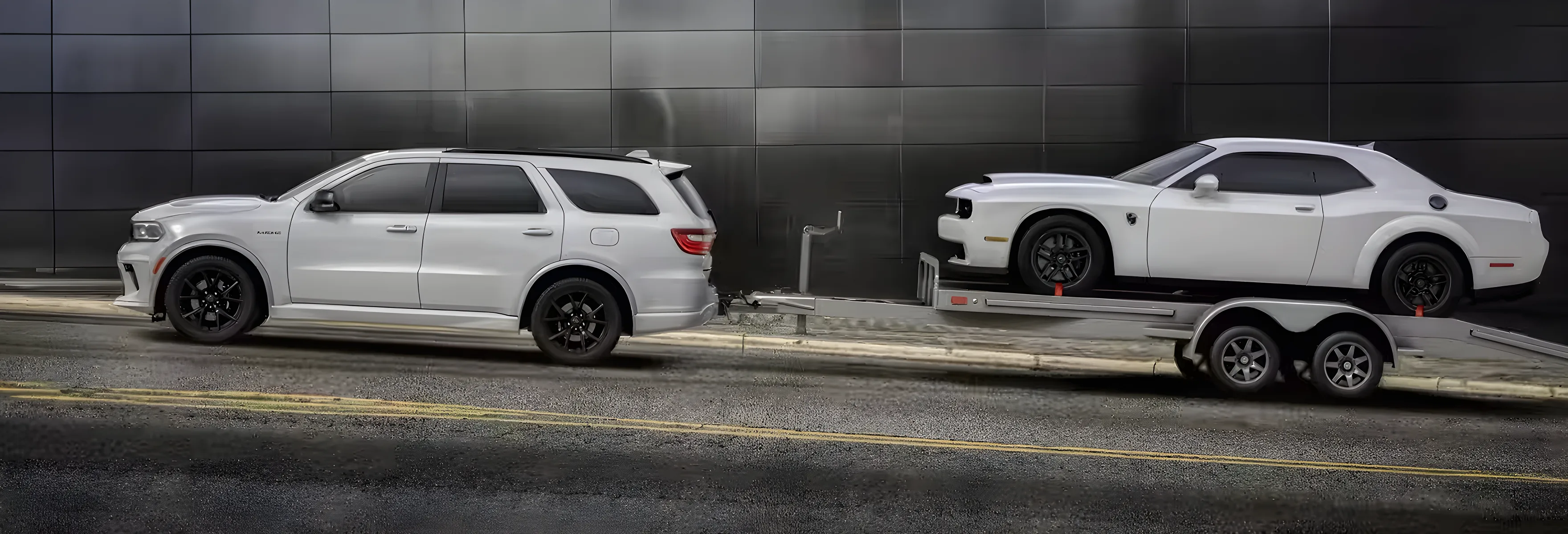 White Dodge Durango towing a trailer loaded with a white Dodge Charger