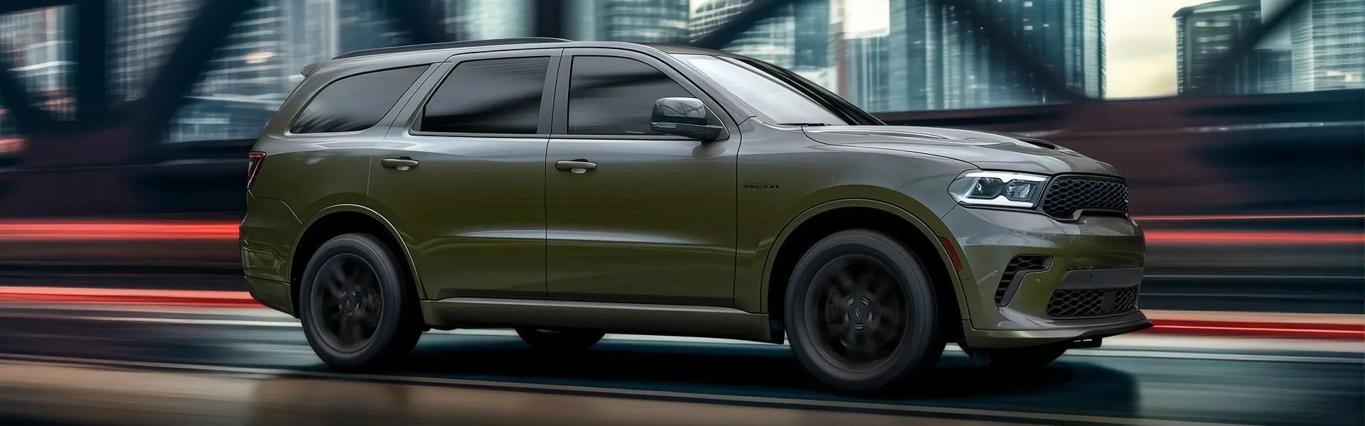 Olive Dodge Durango driving past a city skyline with motion blur