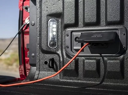 Extension cord plugged into the 120-volt bed outlet of a red RAM 1500