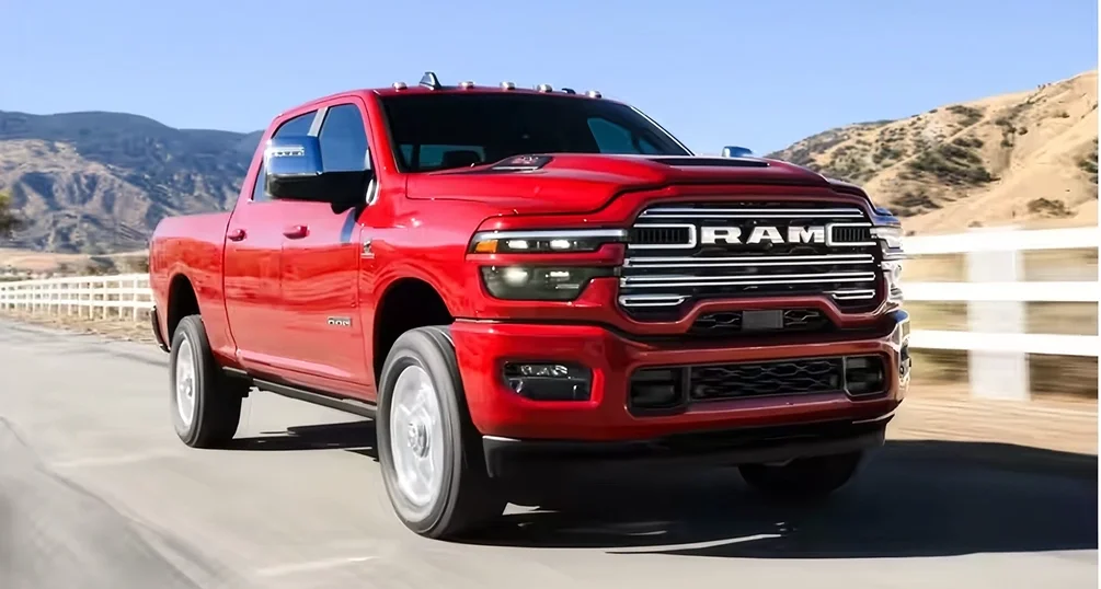 Red RAM 2500 driving past a white ranch fence with hills in the distance
