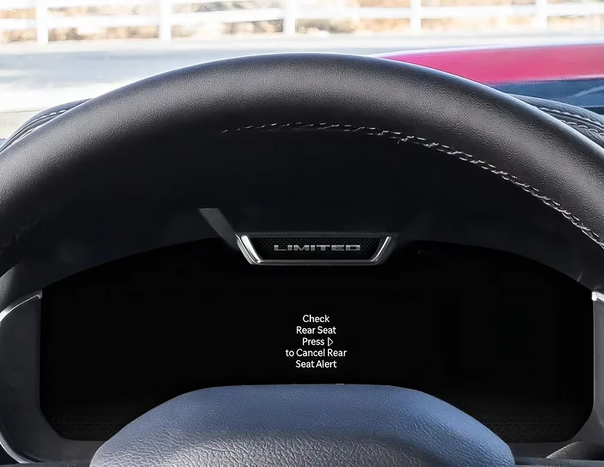 RAM digital cluster showing a Check Rear Seat reminder message behind the steering wheel