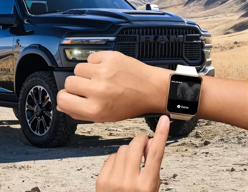 Person tapping a smartwatch to start a black RAM 2500 parked on a dirt trail