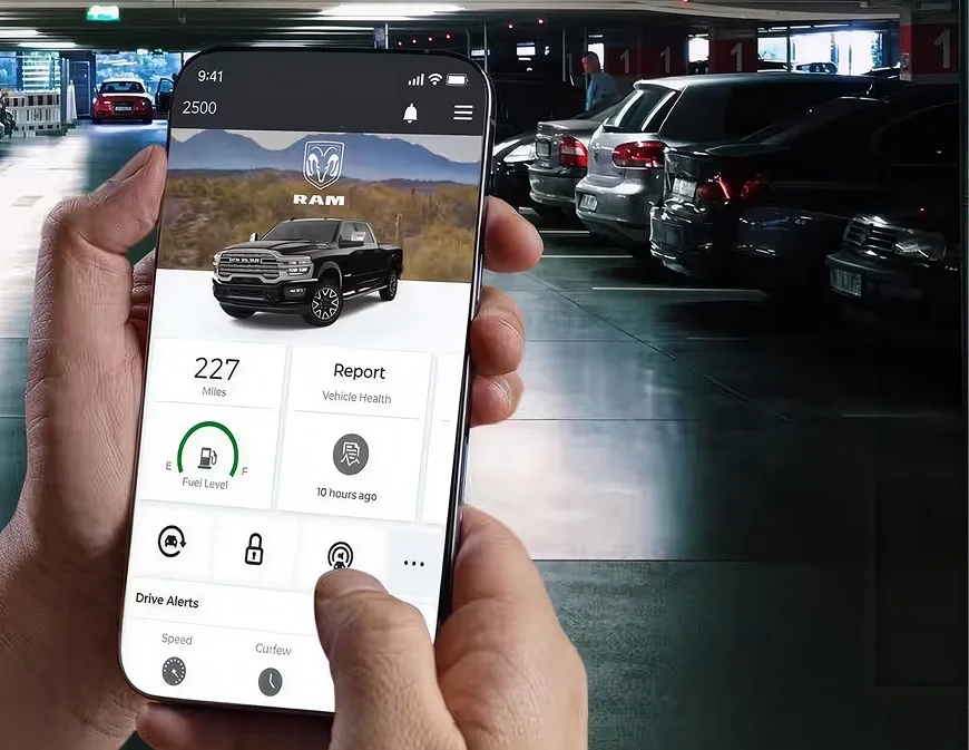 Hands holding a phone with the Ram app in a parking garage with headlamps flashing ahead