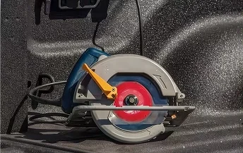 Corded circular saw resting in the spray-lined bed of a RAM 2500