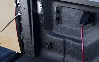 Red extension cord plugged into the 115-volt power outlet inside the RAM 2500 bed