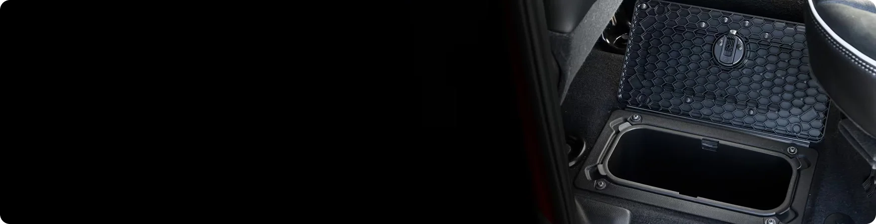 Open RAM in-floor storage bin behind the rear seats of a RAM 3500 with its textured lid raised