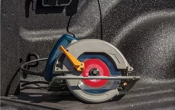 Corded circular saw resting in the spray-lined bed of a RAM 3500