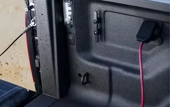 Red extension cord plugged into the 115-volt power outlet inside the RAM 3500 bed