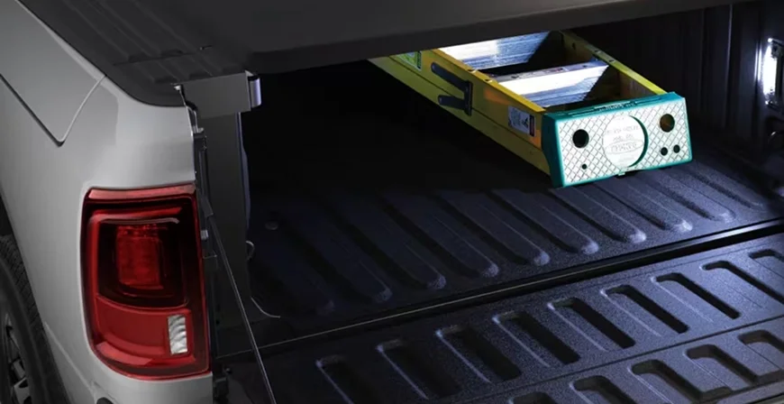LED bed lighting illuminating a ladder and level stored in the bed of a RAM 3500 at night