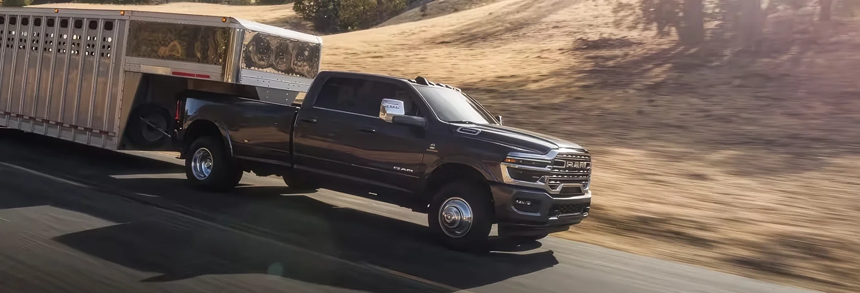 Dark RAM 3500 towing a livestock trailer at speed on a desert highway