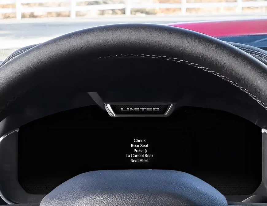 RAM digital cluster showing a Check Rear Seat reminder message behind the steering wheel