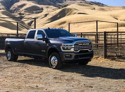 Dark gray dually RAM 3500 parked in a dirt corral with a wood fence and golden hills