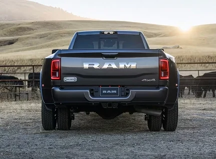 Rear view of a dark gray dually RAM 3500 parked in a pasture with cattle grazing at sunset