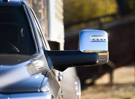 Close-up of a chrome tow mirror on a gray RAM 3500 with a trailer visible behind it