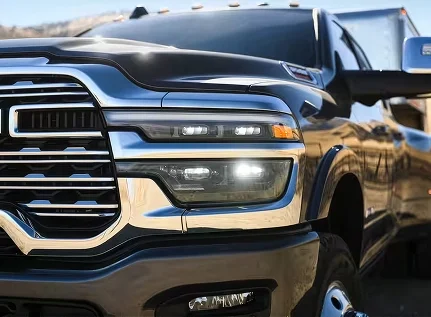 Close-up of the chrome grille and LED headlamp of a dark RAM 3500 hitched to a trailer