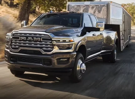 Black RAM 3500 towing a livestock trailer through a wooded area