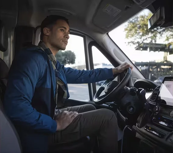 Driver seated in a RAM ProMaster cabin with the steering wheel and touchscreen visible