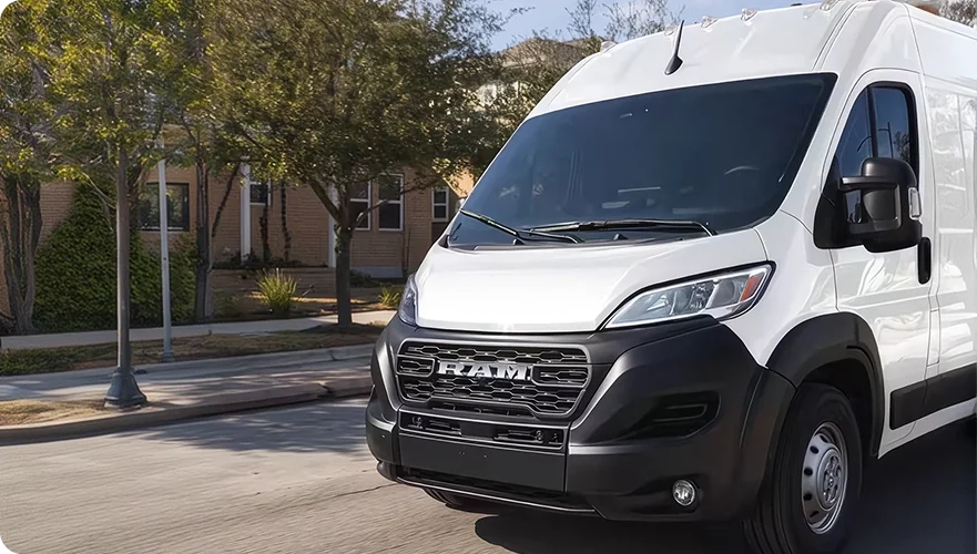 White RAM ProMaster cargo van parked on a residential street lined with trees