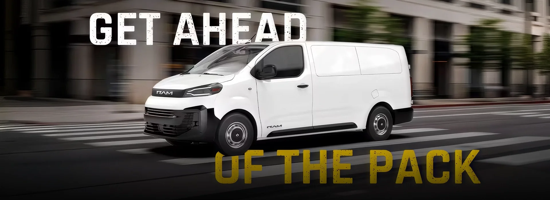 White RAM ProMaster City cargo van driving across a crosswalk on a blurred city street