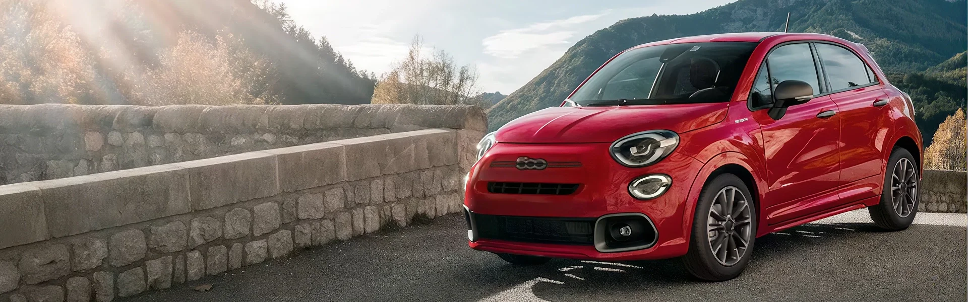 Red FIAT 500X parked on a mountain overlook with hills in the distance