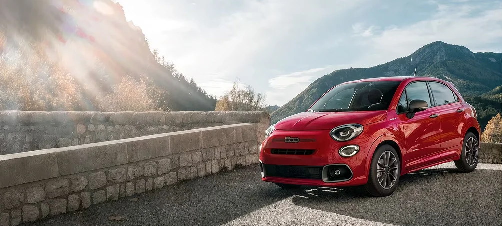 Red FIAT 500X on a mountain road with a rock face behind it
