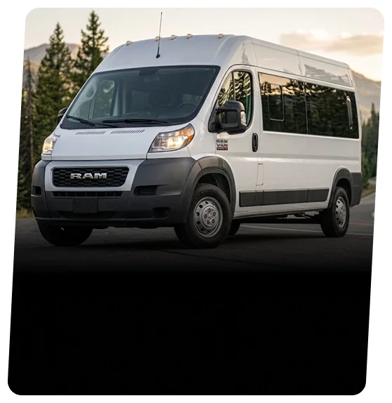 White RAM ProMaster high-roof van parked on a road in front of pine trees