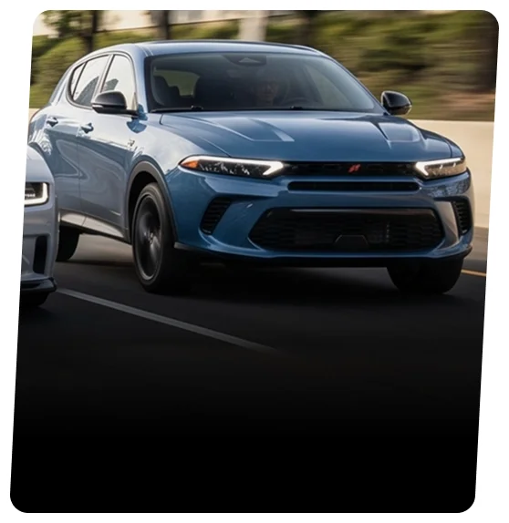 Blue Dodge Hornet plug-in hybrid driving with a city skyline behind it