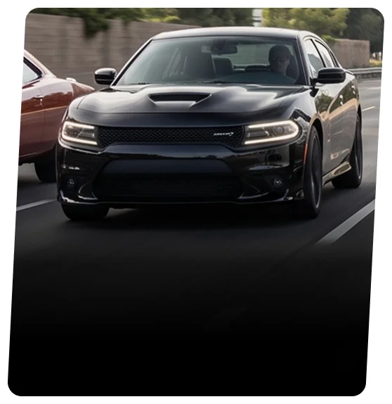 Black Dodge Charger sedan on a city street at speed