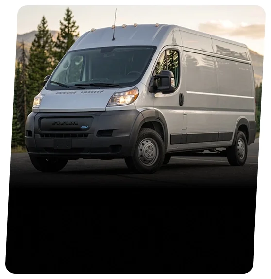 White RAM ProMaster EV high-roof cargo van parked in front of evergreen trees