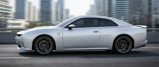 Silver all-electric Dodge Charger Daytona travelling past a city skyline
