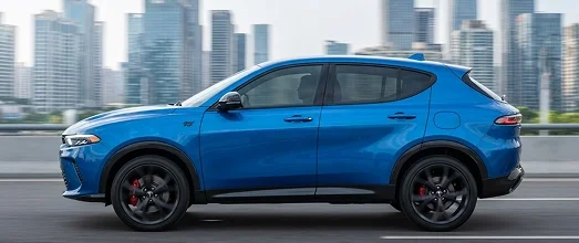 Blue Dodge Hornet plug-in hybrid travelling past a city skyline