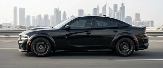 Black Dodge Charger sedan travelling past a city skyline