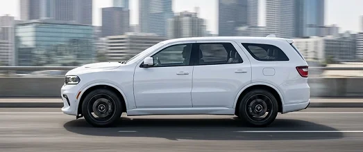 White Dodge Durango SUV travelling past a city skyline