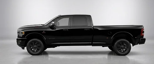 Black RAM heavy-duty crew cab pickup shown in profile on a studio floor