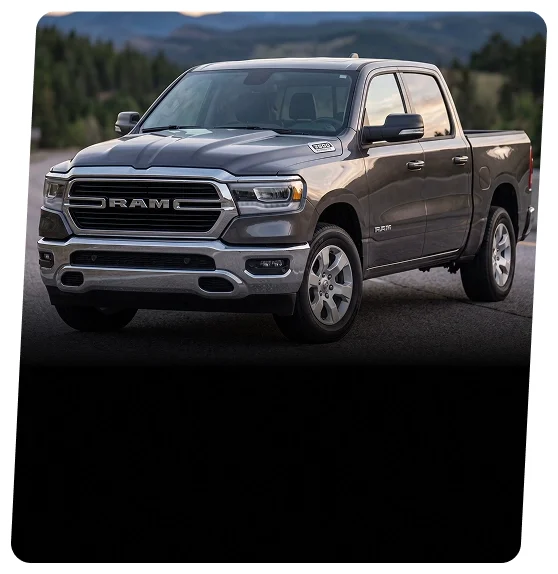 Gray RAM 1500 crew cab pickup on a forest road, front three-quarter view